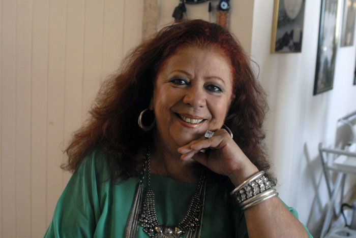 Mulher branca de cabelos ruivos, usando roupa verde.