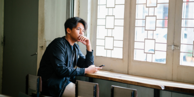 homem olhando pensativo pela janela