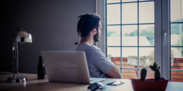 Homem olhando pela janela pensativo
