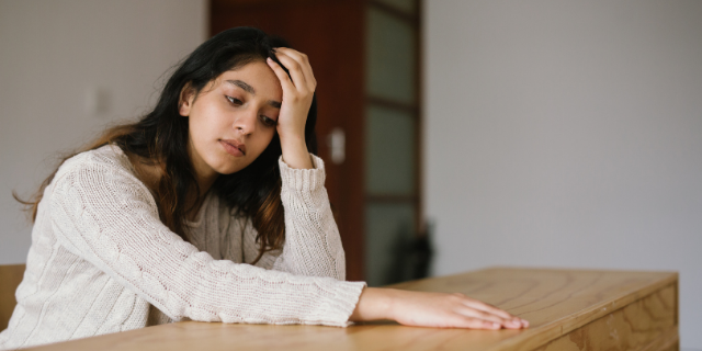 Garota chateada e pensativa sentada na mesa
