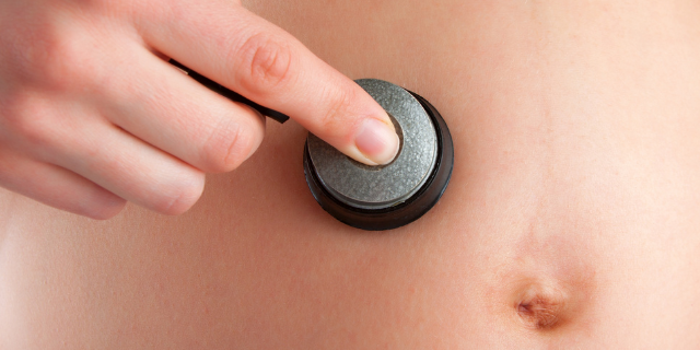 Mulher grávida colocando estetoscópio na barriga 