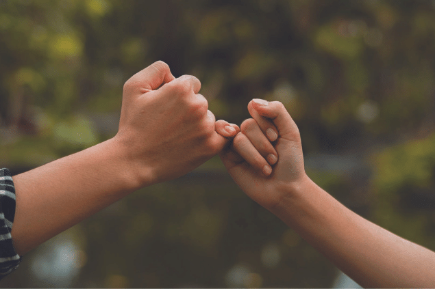 Duas mãos fazendo um gesto de promessa com os mindinhos