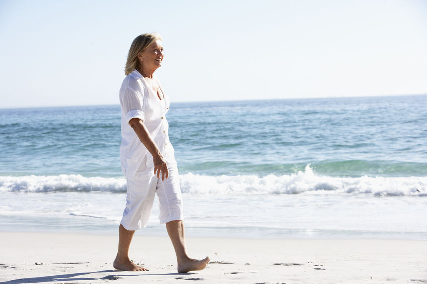 Idosa caminhando na praia