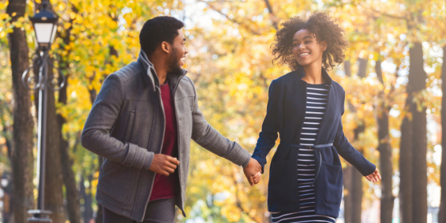 Casal caminhando e sorrindo no parque