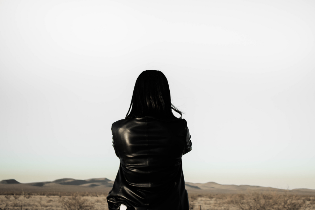 Mulher de costas olhando pensativa para o horinzonte