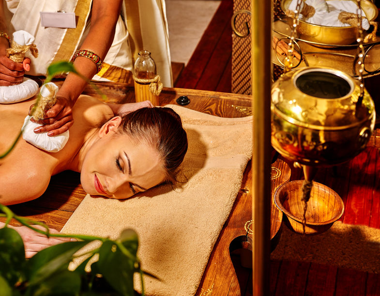 Mulher branca deitada recebendo o tratamento da ayurverda.