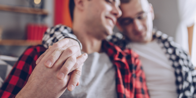 Casal sentados juntos no sofá abraçados e de mãos dadas