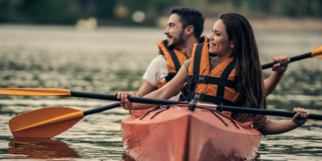 Casal feliz remando de canoa em um rio