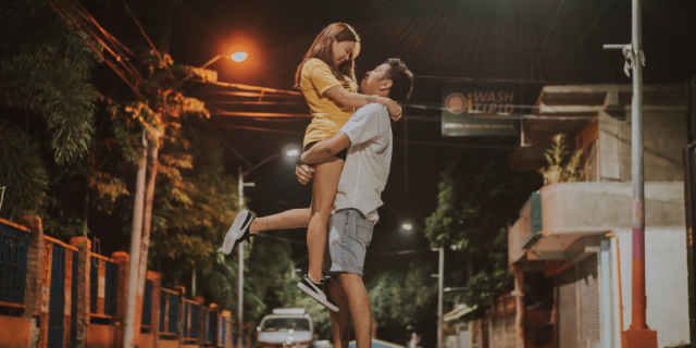 Casal abraçados na rua com a garota sendo erguida no colo