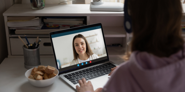 Aluna assistindo aula online de professora sorridente