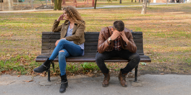 Mulher e homem brigados sentados longe no banco 