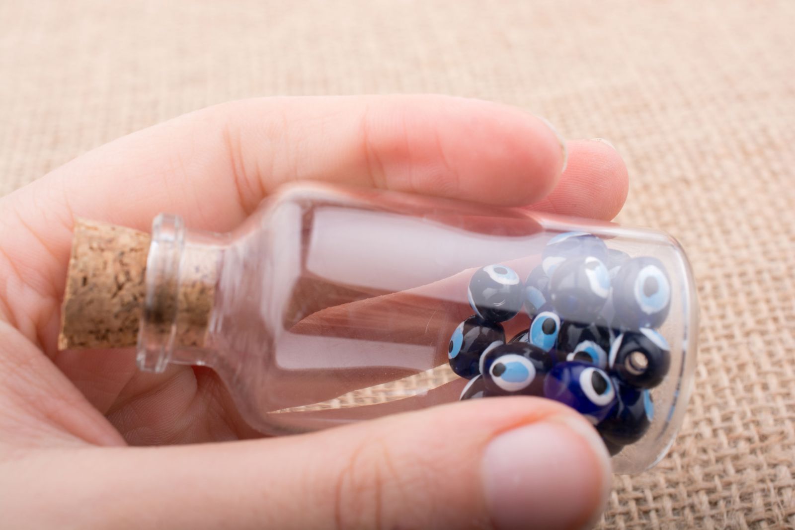 Pessoa segurando frasquinho com olho grego