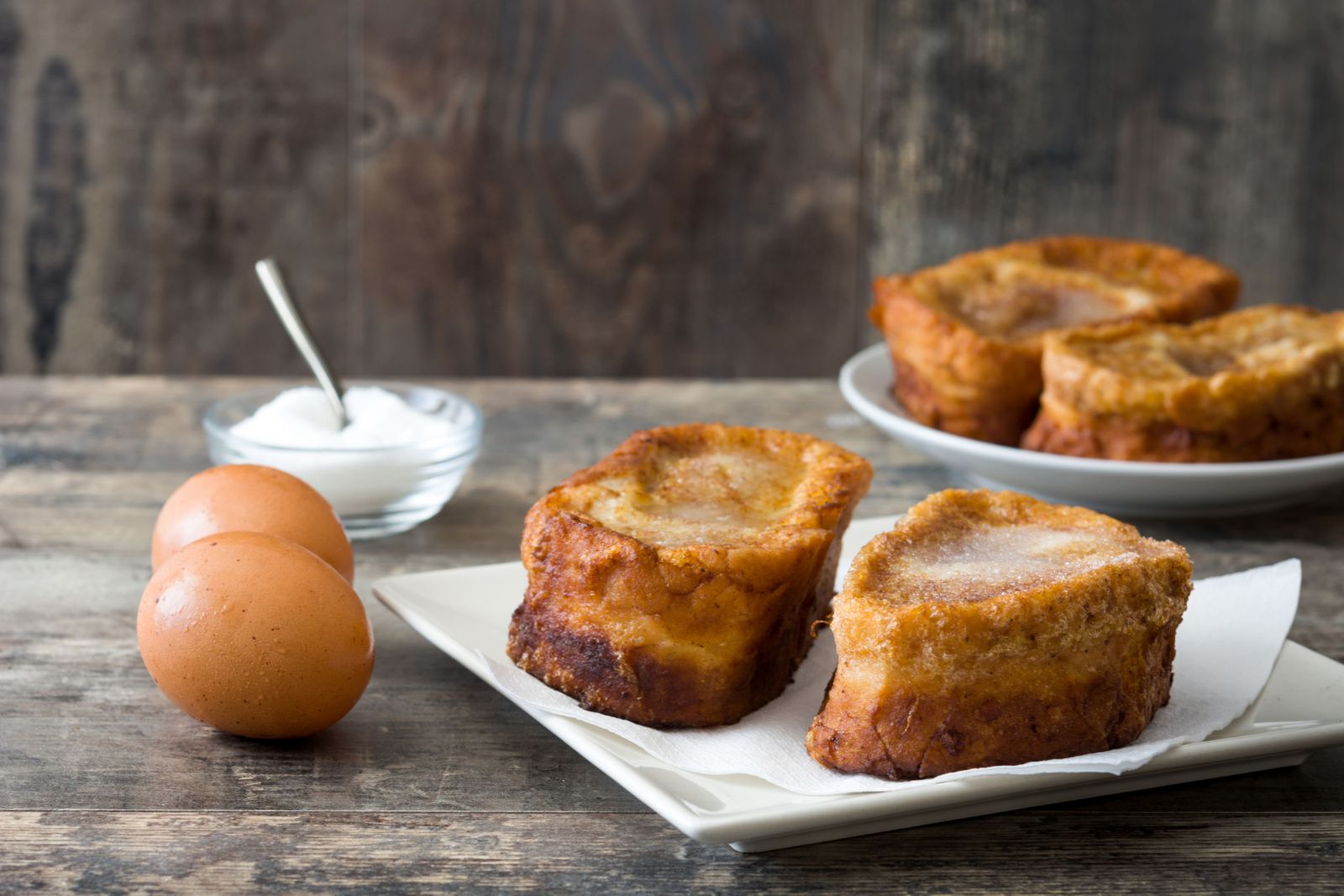 Rabanadas ao lado de um ovo e um potinho com creme