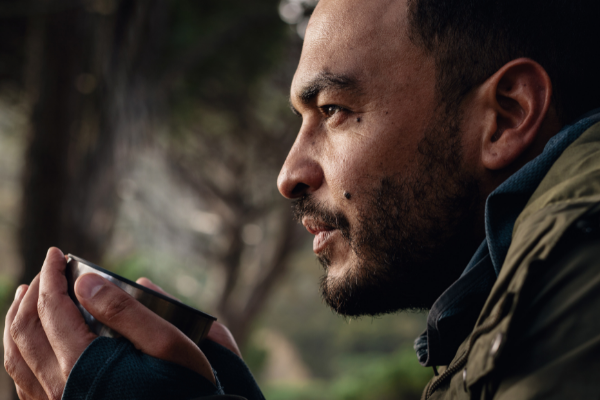 Homem olhando fixamente para o horizonte enquanto segura uma caneca com as duas mãos