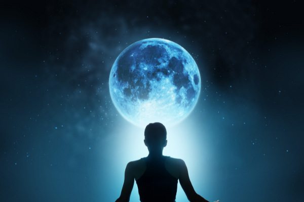 Uma mulher sentada em frente a Lua Cheia