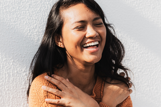 Mulher jovem sorrindo e se auto abraçando