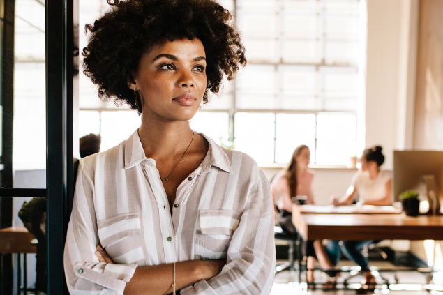 Mulher de braços cruzados refletindo enquanto olha para o lado esquerdo