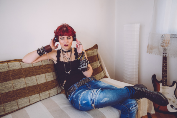 Mulher sentada no sofá enquanto escuta rock em seus fones de ouvido