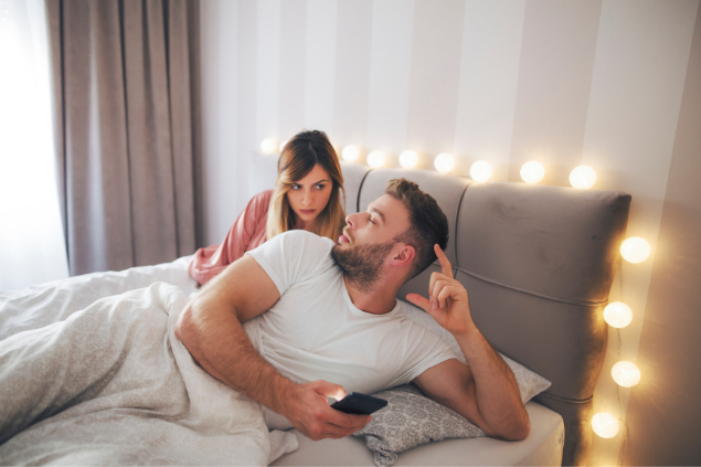 Mulher deitada com ciúme olhando o celular do marido