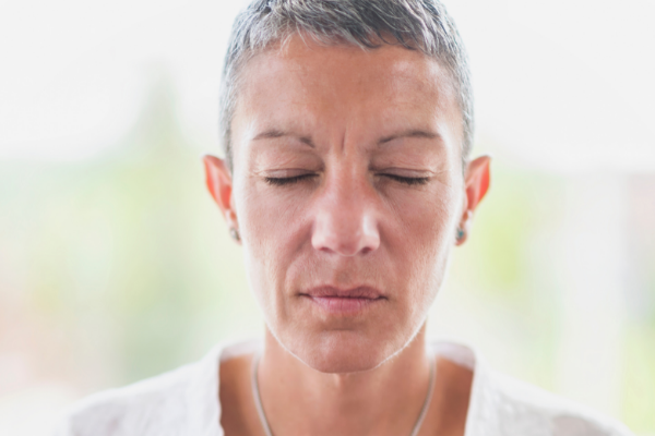 Mulher de olhos fechados enquanto medita