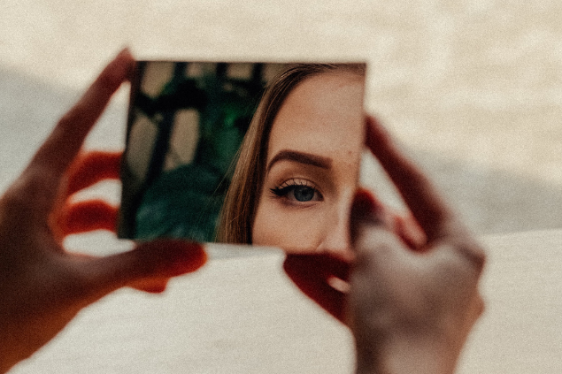 Mulher se olhando em um pedaço de espelho