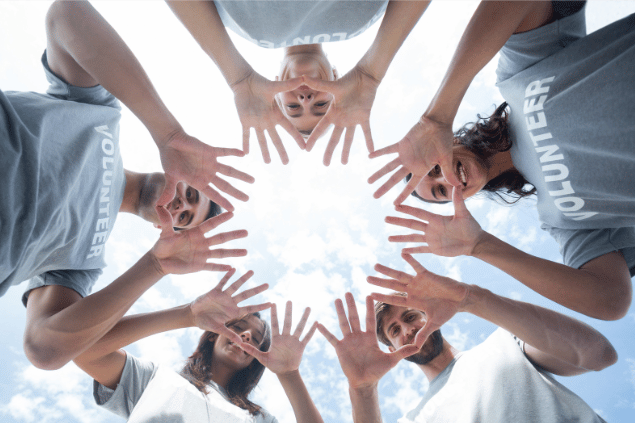 Voluntários com as mãos reunidas, formando um globo. 