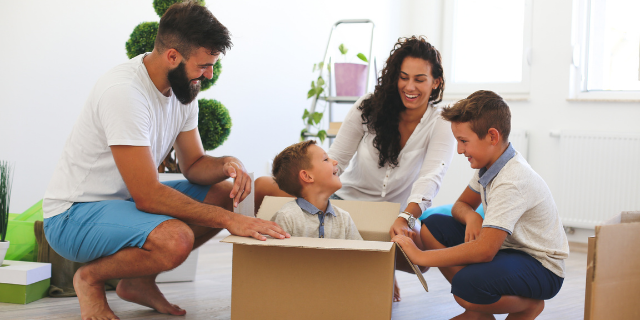 Família sorrindo e brincando com caixa de papelão