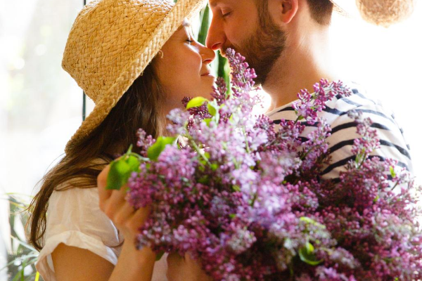 Casal de olhos fechados segurando um buquê de flores