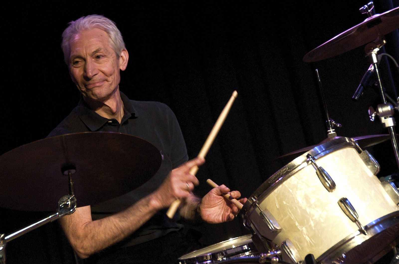 Charlie Watts segurando baquetas da bateria e sorrindo