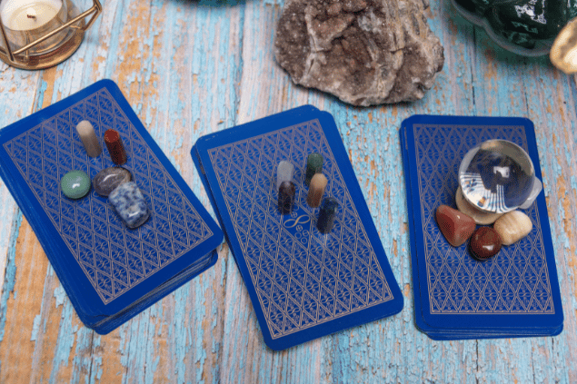 Algumas cartas de Tarot viradas para baixo estão em destaque na imagem. Ao lado, há uma vela e outros objetos.