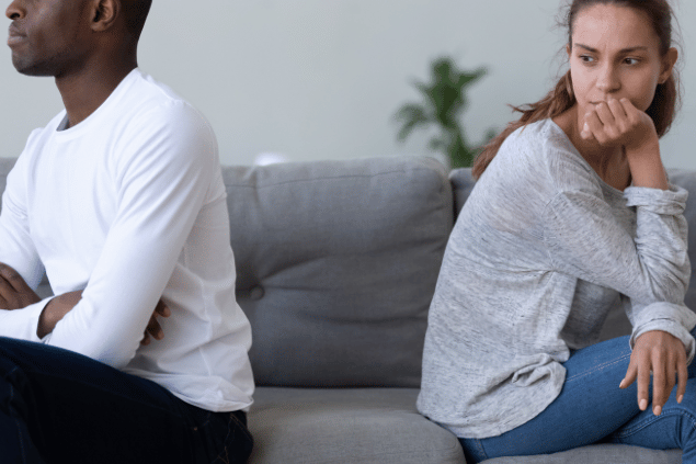 Mulher se sentindo culpada com seu parceiro. Os dois estão de costas um para o outro. 