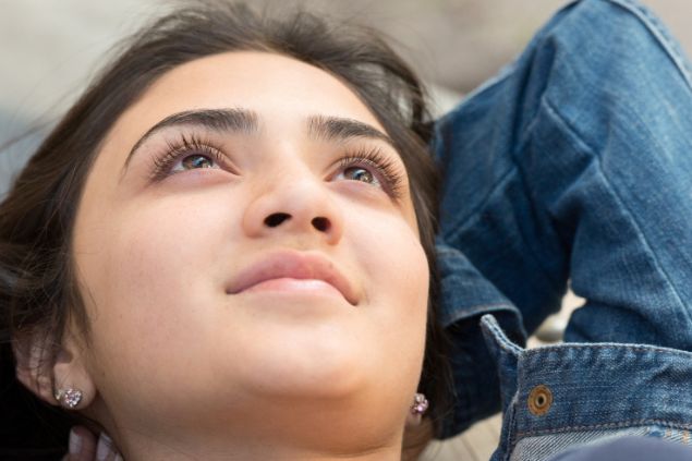 Imagem de uma mulher deitada, pensativa e sorrindo