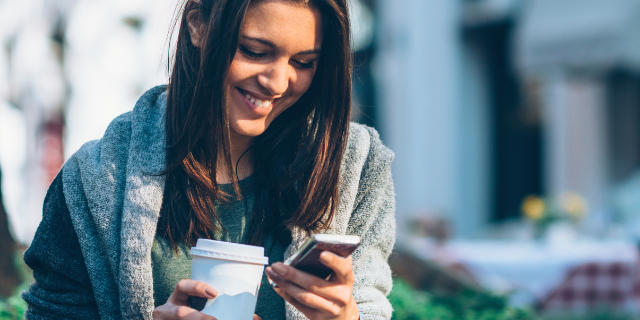 Mulher sorrindo e olhando para o celular