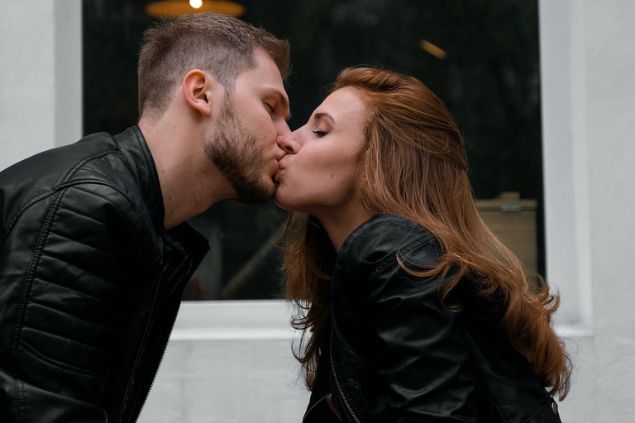 um homem e uma mulher se beijando apoiados na mesa