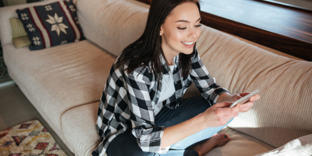 Mulher sentada no sofá e mexendo no celular