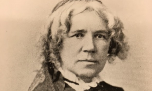 Maria Mitchell olhando para frente usando um vestido