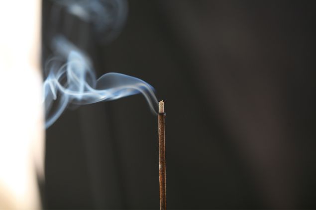 Imagem de um incenso aceso perto de uma janela