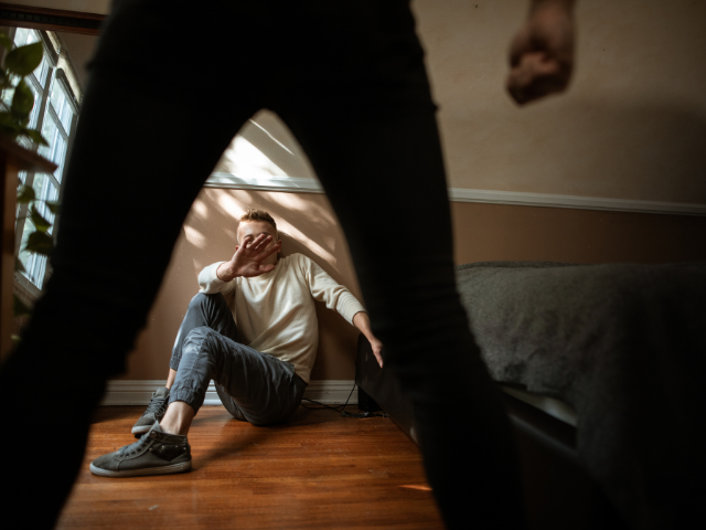 Agressor em frente a vítima assustada e encolhida