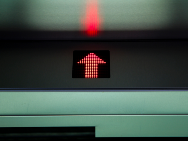 Seta vermelha apontando para cima em elevador