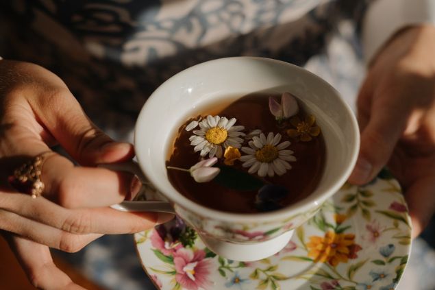 pessoa segurando uma xácara de chá de camomila
