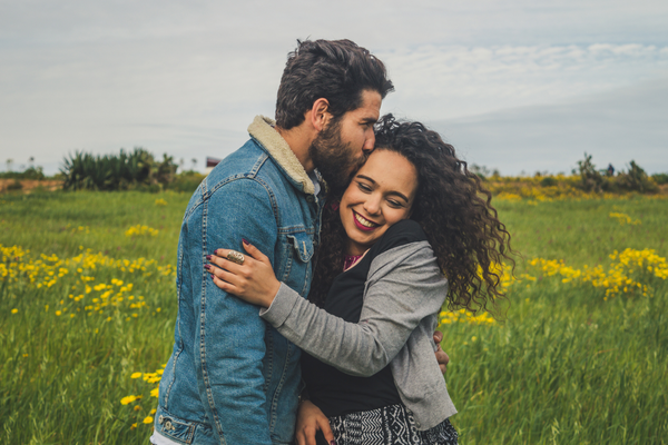 Homem beijando cabeça da mulher ao seu lado 