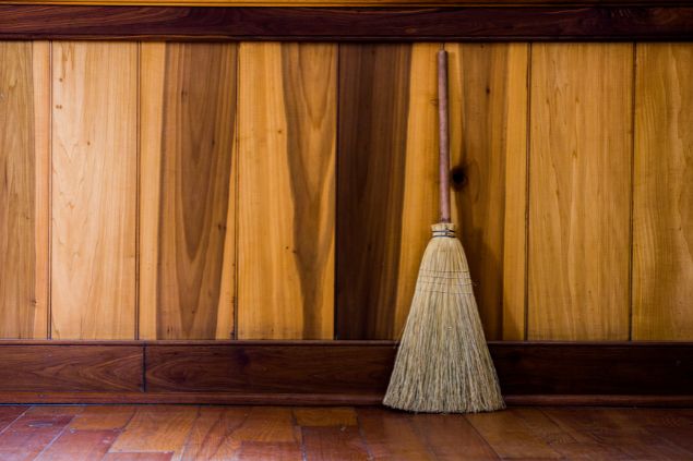vassoura encostada em uma parede de madeira