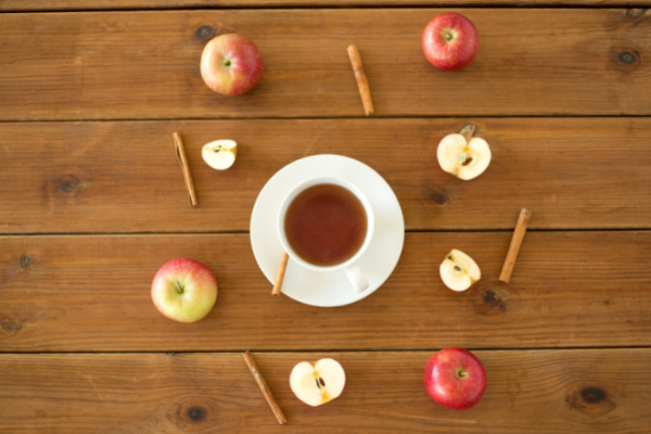 Chá de canela com a fruta e especiaria ao redor.