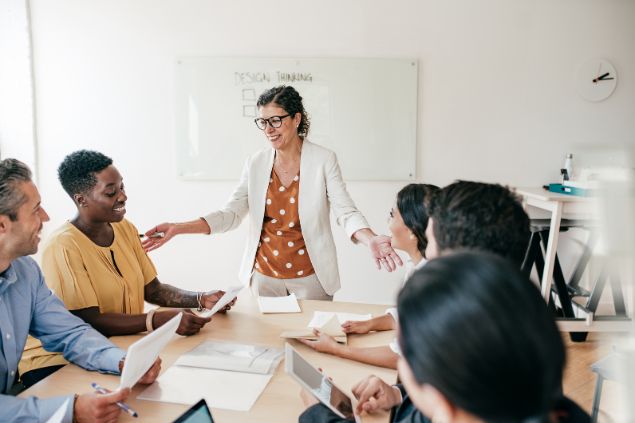 Imagem de uma mulher liderando uma reunião em uma sala de reuniões