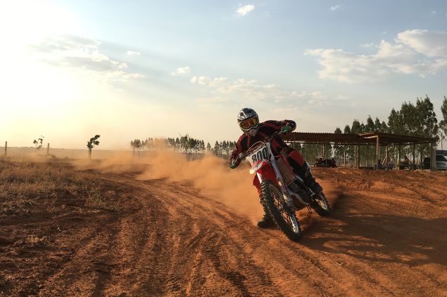 Imagem de um homem fazendo motocross em uma estrada de barro