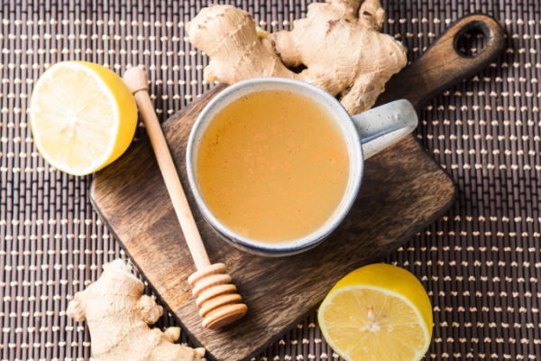 Chá com limão, gengibre e mel ao redor.