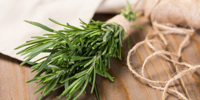 Ramo de alecrim sobre superfície de madeira. 