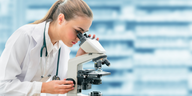 Pesquisadora manipula microscópio. 