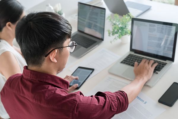 Homem e mulher em frente ao notebook, focados 
