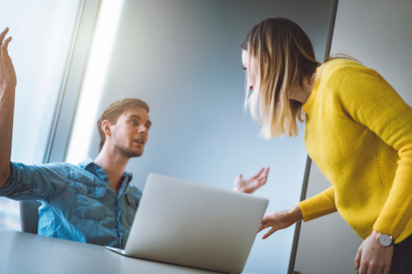 Homem e mulher brancos brigando em ambiente de trabalho.